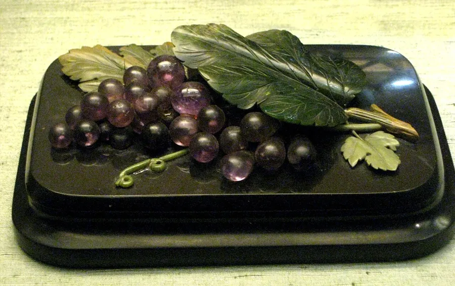 A bunch of amethyst grapes: A paperweight with a bunch of grapes carved in amethyst on serpentine and marble, made by the Ekaterinburg lapidary works and once owned by the Stroganov family.