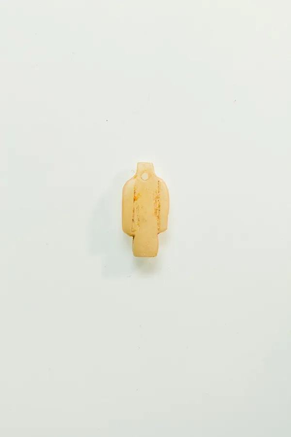A carnelian Isis knot amulet: A tiny tyet amulet of carnelian, 1.1 cm high, from a string of amulets. Egyptian, Third Intermediate Period, About 1080 to 945 BC.