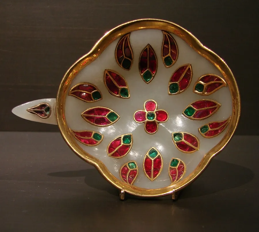 A Mughal jade wine cup set with rubies and emeralds: A wine cup of jade inlaid with gold, rubies and emeralds, made in Mughal India in the 18th century.