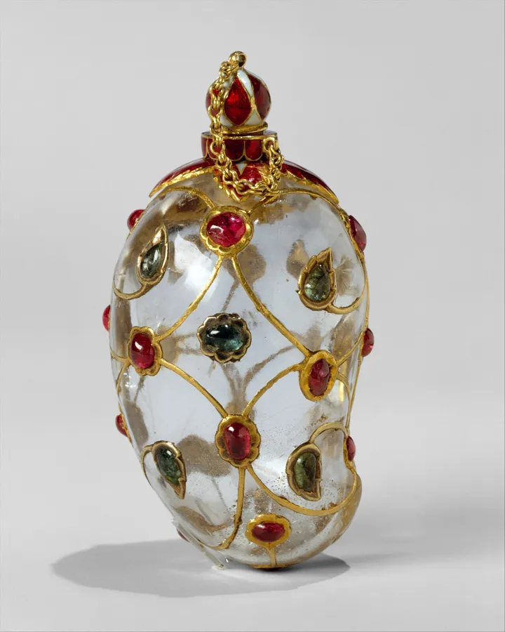 A Mughal mango-shaped flask: A 6.5 cm flask in the shape of a mango, made of two halves of rock crystal held by gold wire scrolls set with rubies and emeralds, with enamel.