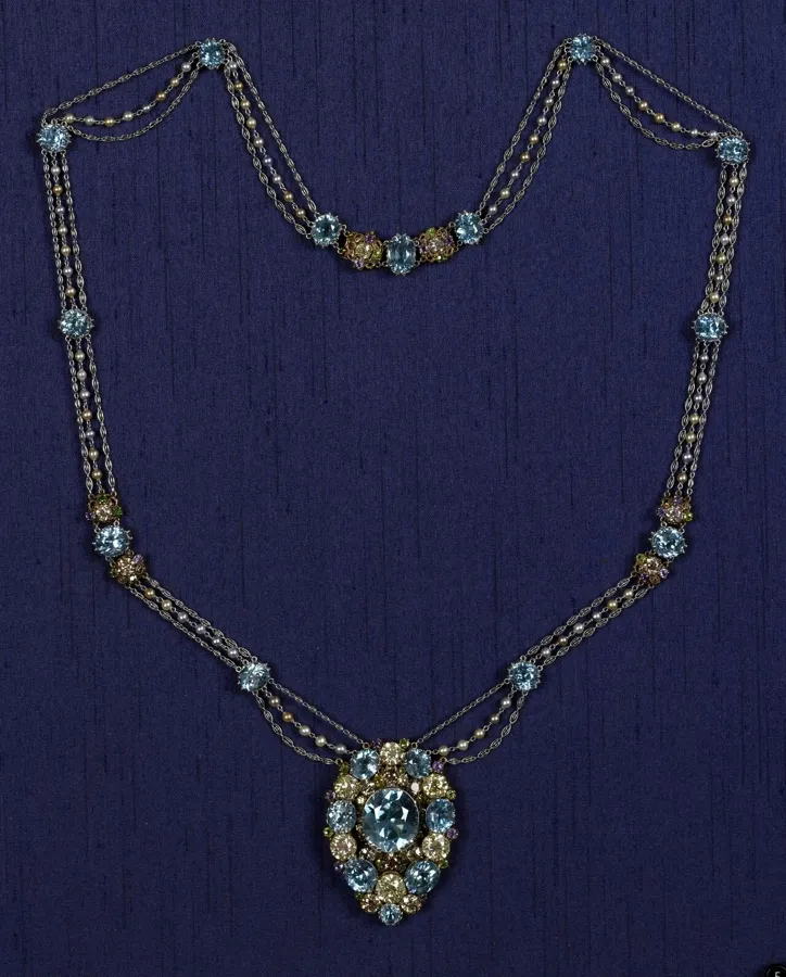 A Tiffany pendant with a blue zircon: A pendant necklace by Tiffany & Co. with a large blue zircon in the centre, surrounded by canary and coloured diamonds, demantoid garnets and amethysts, on platinum chains with coloured pearls.