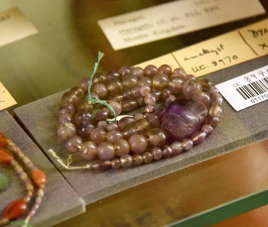 An amethyst scarab necklace: An uninscribed amethyst scarab at the centre of a string of amethyst ball beads, Middle Kingdom Egypt (about 2000 to 1700 BC).