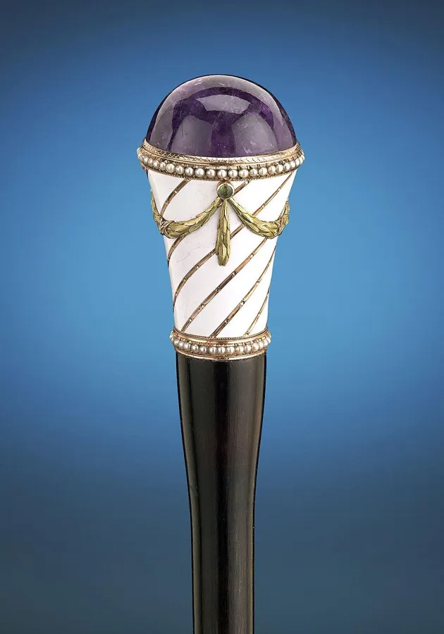 A Fabergé amethyst cane handle: A cane handle of polished amethyst by Fabergé, with white enamel, rose and yellow gold and a string of pearls, about 1890 to 1898.