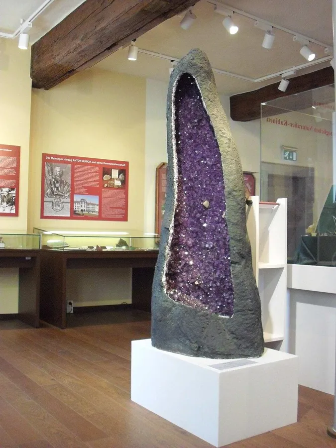 A giant amethyst geode: A geode from Rio Grande do Sul, Brazil, taller than a person, lined with amethyst and a few calcite crystals.