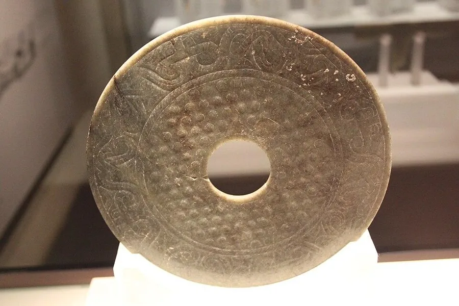 A Han jade bi disc: A flat jade disc with a hole in the centre, carved with rows of raised spirals, Western Han dynasty (206 BC to AD 9).