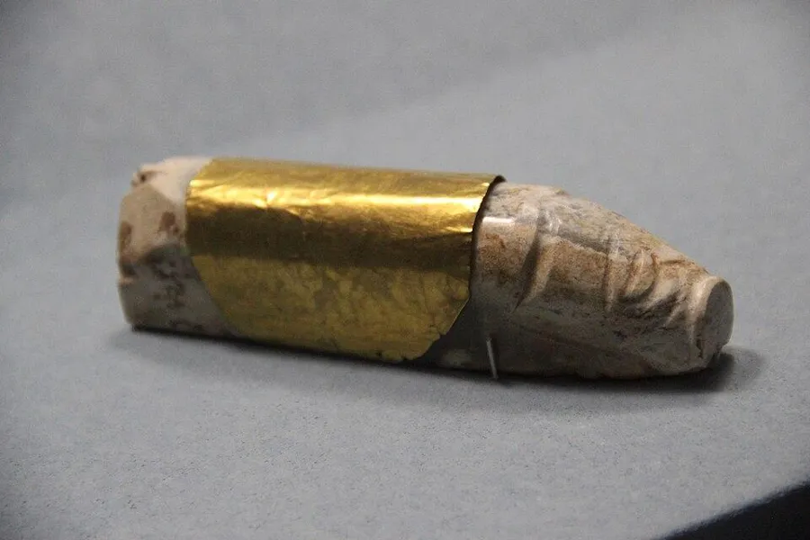 A Han jade pig with gold foil: A small jade pig wrapped in gold foil, placed in the hand of the dead, Han dynasty.