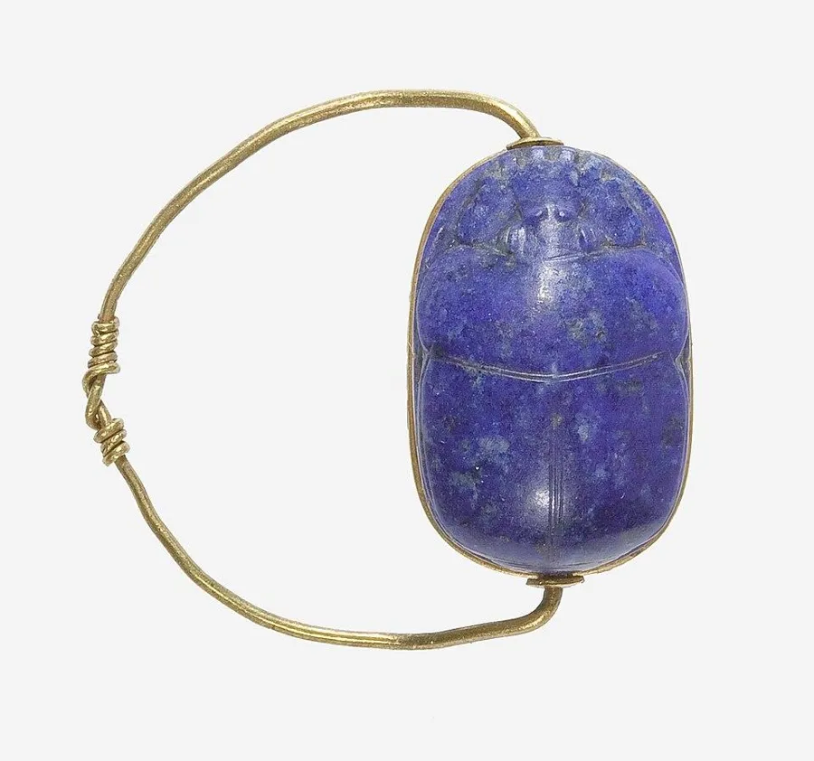 A lapis scarab ring: A gold wire finger ring holding a lapis scarab that could swivel to show its base, ancient Egypt.
