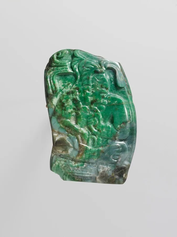 A Maya jade pendant of a seated lord: Jadeite carved with a seated ruler, Maya, Late Classic period.