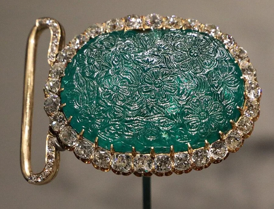 A carved Mughal emerald: A large Colombian emerald carved with flowers in India in the 17th century, later set in a European mount.