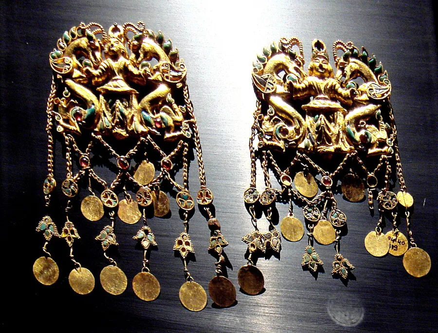 The Master of Dragons pendants: A pair of gold pendants showing a figure holding two dragons, inlaid with turquoise, garnet, lapis lazuli and carnelian and hung with pearls, from Tomb II at Tillya Tepe.