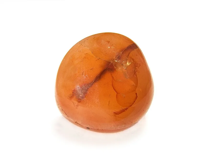 A natural carnelian pebble: translucent orange chalcedony as it is found in river gravels and old lava.