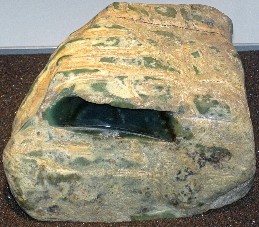 A jadeite boulder from Myanmar with a "window" ground into its skin, the way buyers judge the green inside before cutting.