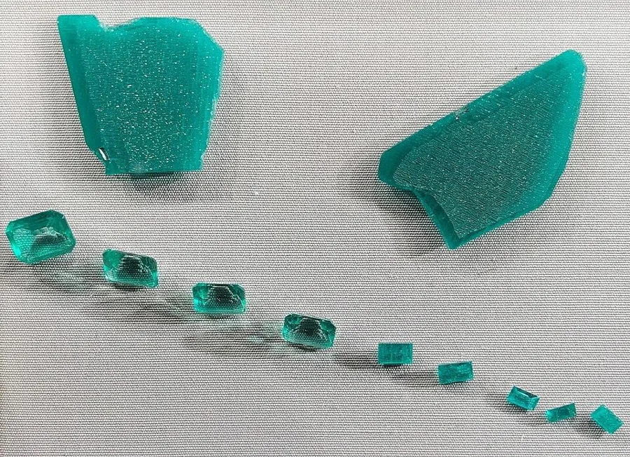 Hydrothermal lab emerald: two grown slabs and the stones cut from them (Natural History Museum, Vienna).