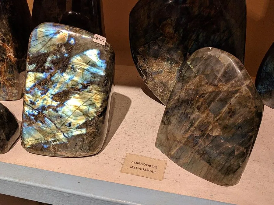 Two polished labradorites in a shop in New Mexico: one blazes blue and gold, the other looks plain grey. Turn either one and they swap.