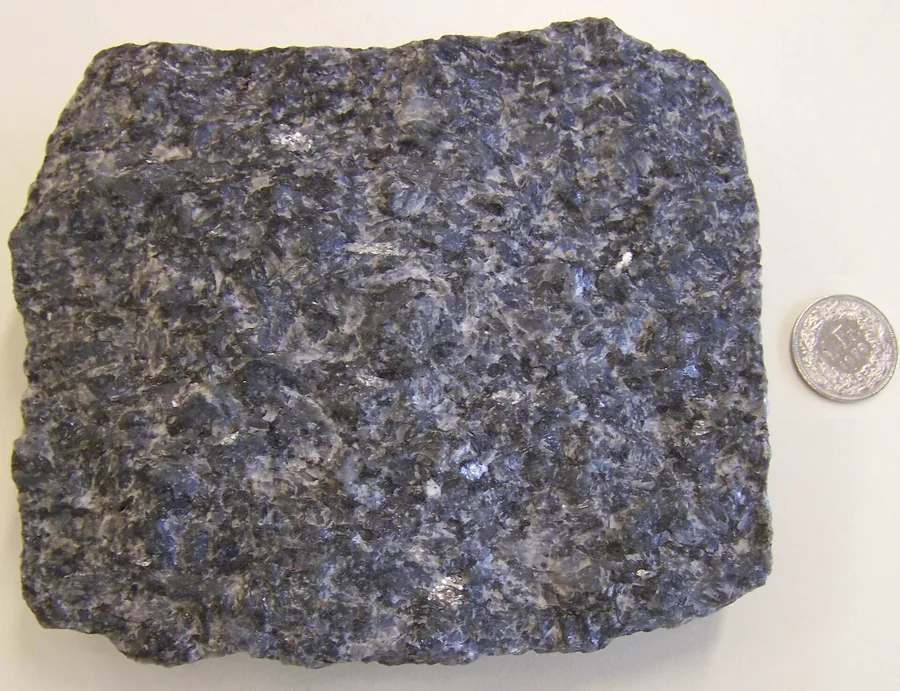 A broken piece of larvikite: grey-blue and coarse-grained, with feldspar crystals you can see by eye.