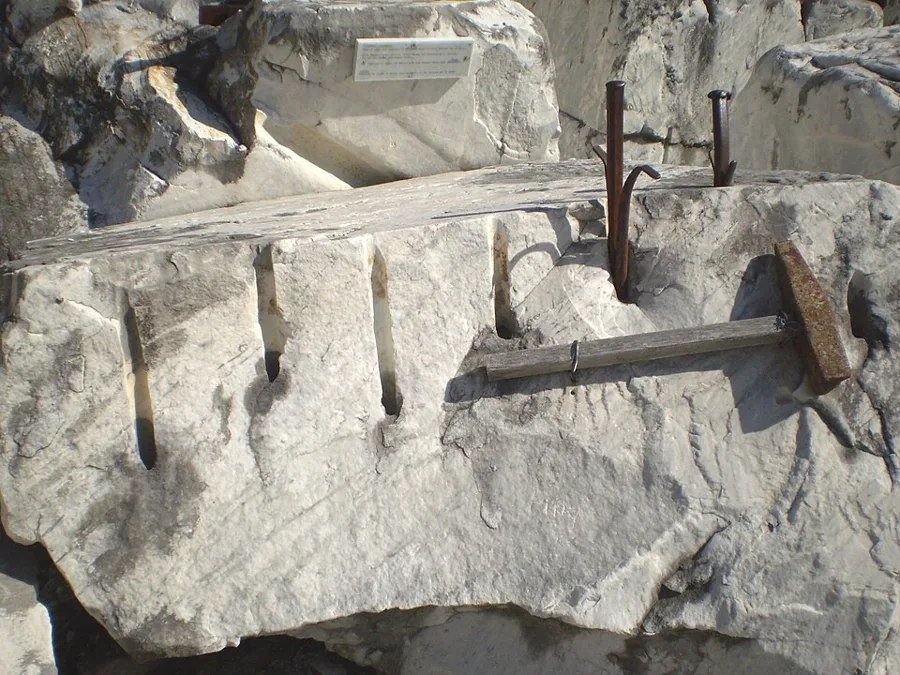 The old way to split marble: holes drilled in a line, then wedges hammered in until the block cracks along the line.